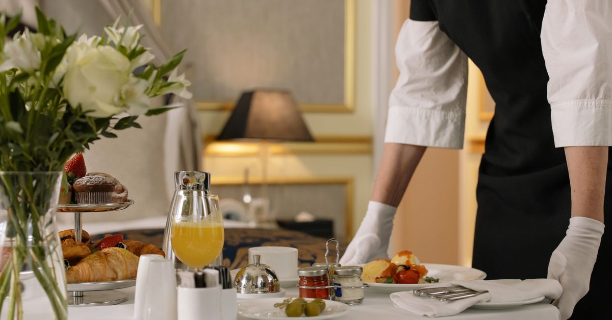 A luxurious hotel room showcasing an elegant room service breakfast setup with fresh flowers and a platter of assorted pastries.